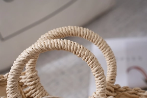 Detailaufnahme des spiralförmigen Papierseilgriffs einer beigen handgefertigten Strandtasche