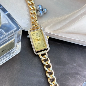 Macro view of a gold square quartz watch with rhinestone bezel on beige silk fabric