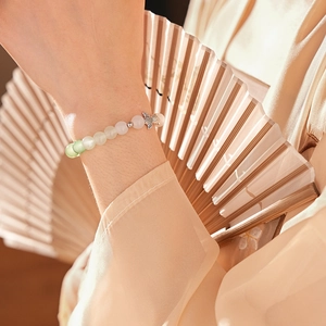 Close-up of a gradient nephrite chalcedony fish charm bracelet worn on a wrist
