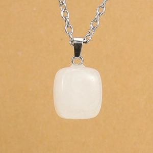 Vertical view of a square white stone pendant with a silver chain against a yellow backdrop