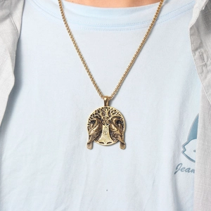 Close-up of golden vintage Viking crow and tree of life pendant on a box chain