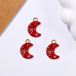 Close-up of red crescent moon pendants with blue and black rhinestones for jewelry making