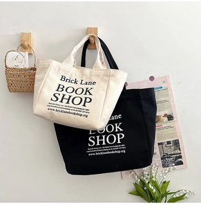 Close-up of black and beige canvas tote bags with London bookstore print on a hook