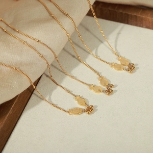 Gold stainless steel necklace with double fish koi pendant and beads on wooden tray