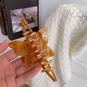 Macro shot of an amber butterfly-shaped acetate hair claw clip with a glossy finish
