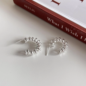 Detailed close-up of 925 sterling silver spiral spring stud earrings on a minimalist background