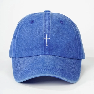 Close-up of cross embroidery on vintage washed denim baseball cap with fabric texture