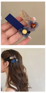 Dettaglio di fermagli per capelli con fiori blu opachi e molletta in resina