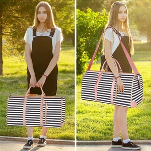 Black and white striped foldable travel bag with pink straps on sunny grass background