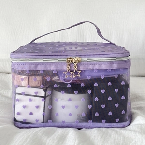 Detail of purple mesh makeup bag featuring velvet hearts and star zipper pulls