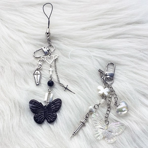 Detail of Y2K gothic black butterfly and iridescent charms on plush background