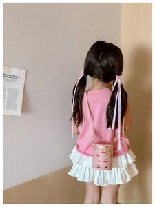 Detailed back view of a pink cherry print bucket bag worn by a girl in soft light