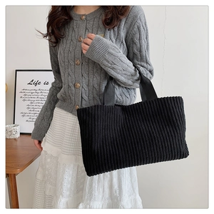 Fashionable black corduroy tote bag styled with casual grey knit cardigan for daily commute