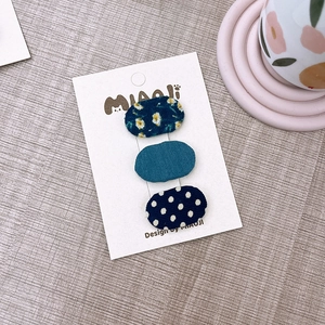 Set di tre piccole mollette BB in tessuto a fiori e pois su cartoncino da esposizione