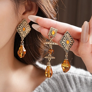 Close-up of vintage geometric bronze earrings with amber stones and teardrop beads