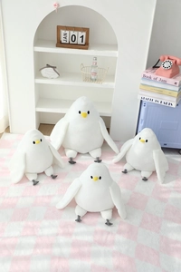Set of soft white pigeon plush toys in different sizes on a cozy decorative blanket