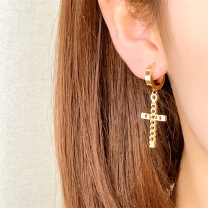 Close-up of a minimalist gold cross pendant earring worn for a stylish fashion look