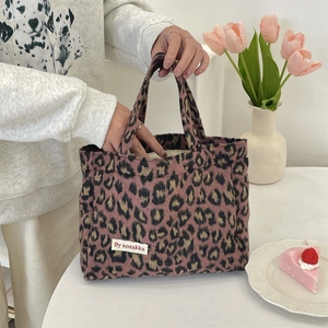 Close-up of leopard print plush handbag with white label on a cozy desktop