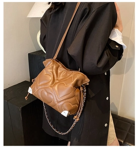 Detail of dark brown leather bucket bag featuring heart quilting and silver corner guards