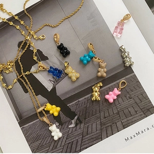 Flat lay of colorful resin bear necklaces with gold chains on a fashion magazine