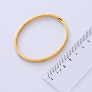 Polished gold stainless steel oval bangle shown with a ruler for size measurement