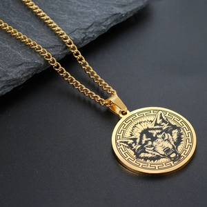 Close-up of golden wolf head pendant with Greek fret border on black textured stone