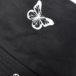 Vue détaillée de la broderie papillon blanc sur un chapeau en sergé de coton noir