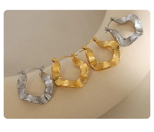 Detailed view of textured gold and silver wavy earrings on a display stand
