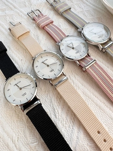 Detail view of four minimalist quartz watches with nylon fabric straps in multiple colors