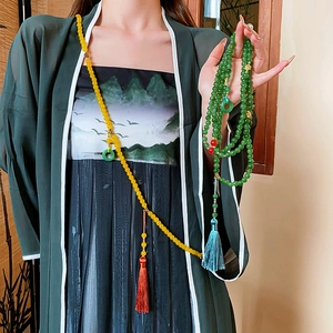 Détail de longs colliers perlés avec glands et pendentif en jade sur un mannequin