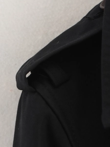 Gros plan des épaulettes et de la texture en sergé d'un trench-coat noir élégant