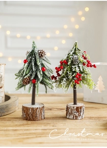 Close-up of mini desktop Christmas trees with red berries and natural wood stump base
