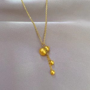 Detailed view of a gold gourd pendant necklace with dangling tassels and beads