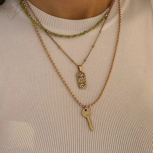 Layered gold necklaces with evil eye pendant and love key on white sweater