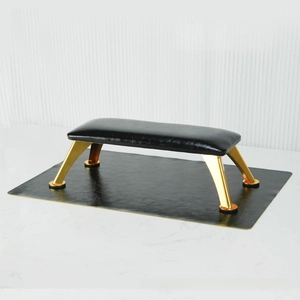 Close-up of black leather nail arm rest with gold metal legs and non-slip pads