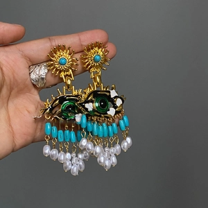 Détail de boucles d'oreilles vintage en résine avec motif soleil, œil émaillé et perles