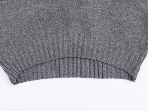 Gros plan du pull en maille grise montrant l'ourlet côtelé et la texture en laine mélangée