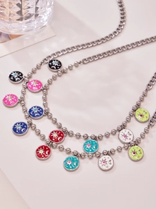 Detail of double-layer stainless steel necklace with sun and moon enamel charms