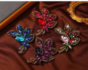 Detailed view of vintage leaf brooches with marquise rhinestones on silk fabric