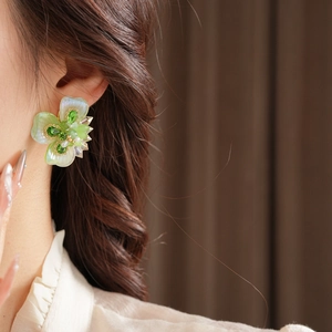 Gros plan détaillé de boucles d'oreilles fleur vintage avec cristaux verts et nacre