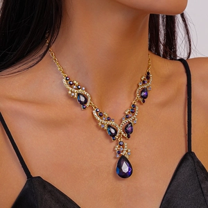 Detail of luxury teardrop purple crystal necklace set with gold finish and rhinestones