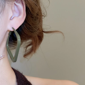 Detail of dark green square enamel earrings worn on model for autumn fashion look