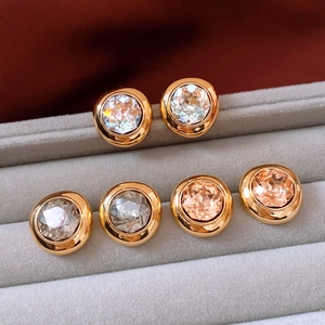 Macro shot of gold oval vintage earrings with multi-color crystals on velvet