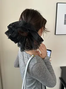 Detail of a large black lace scrunchie with intricate embroidery worn on a bun