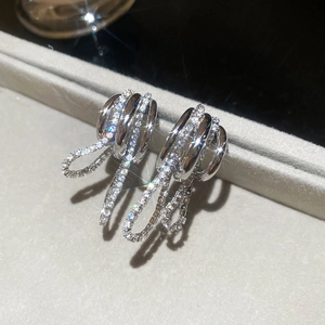 Vue macro de boucles d'oreilles argentées avec cercles superposés, franges et zircons blancs