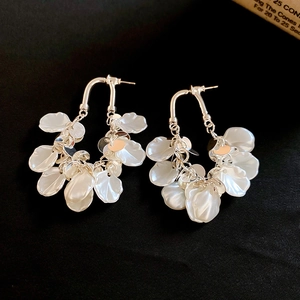 Détail de boucles d'oreilles en U argentées avec pétales nacrés blancs et disques en métal