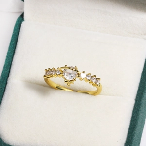 Detail of gold planet ring with white zircon stones in a green velvet gift box