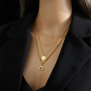 Collier multicouche en titane doré avec pendentifs étoile et lune sur modèle élégant