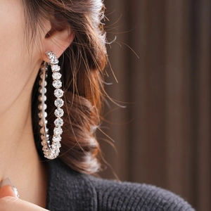 Close-up of a model wearing silver round hoop earrings with sparkling zircon stones