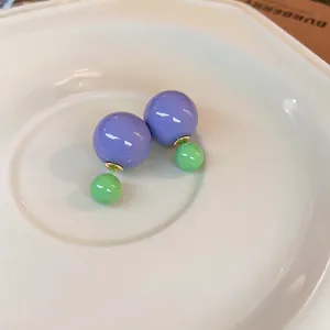 Minimalist purple and green bead earrings on a white ceramic tray for a chic jewelry look